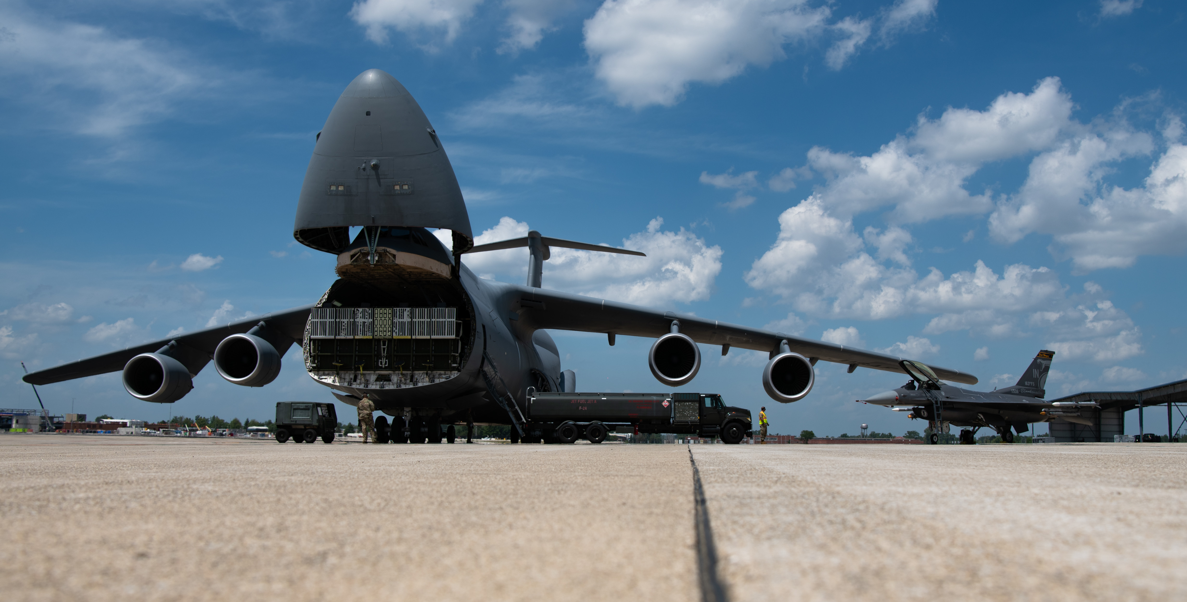 A U.S. Air Force C-5M Super Galaxy aircraft assigned to the 9th Airlift Squadron, Dover Air Force Base, left, sits beside an R-11 fuel truck and an F-16C Fighting Falcon aircraft assigned to the 122nd Fighter Wing on the flight line at the 122nd Fighter Wing, Fort Wayne, Indiana, July 24, 2025