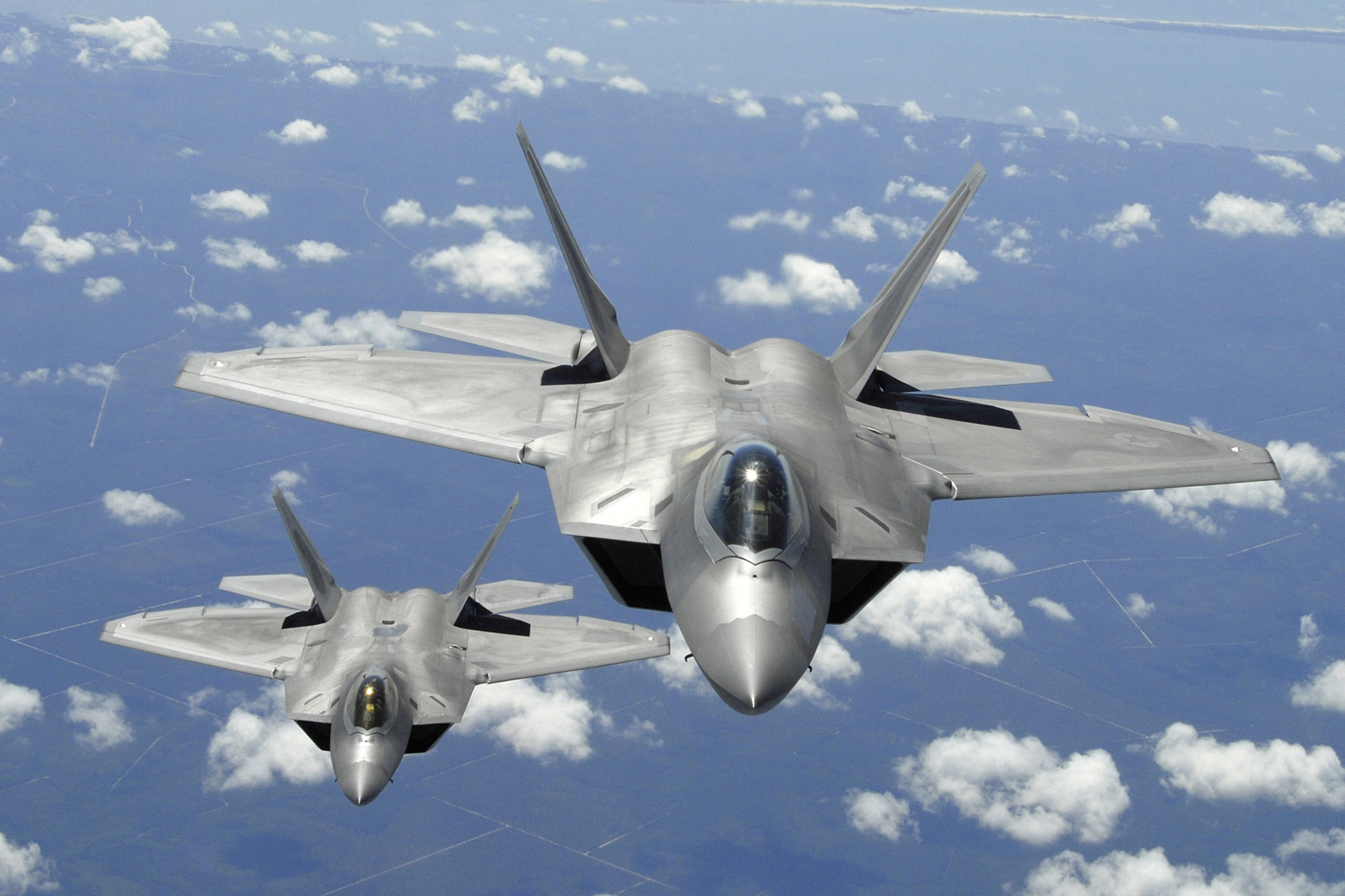 Two U.S. Air Force F-22 Raptor aircraft fly in trail behind a KC-135R Stratotanker aircraft after inflight refueling during a training mission off the coast of Florida on April 2, 2007